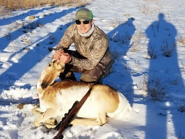 A man kneeling down next to a dead animal.