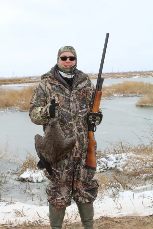 A man holding a gun and a fish in his hand.