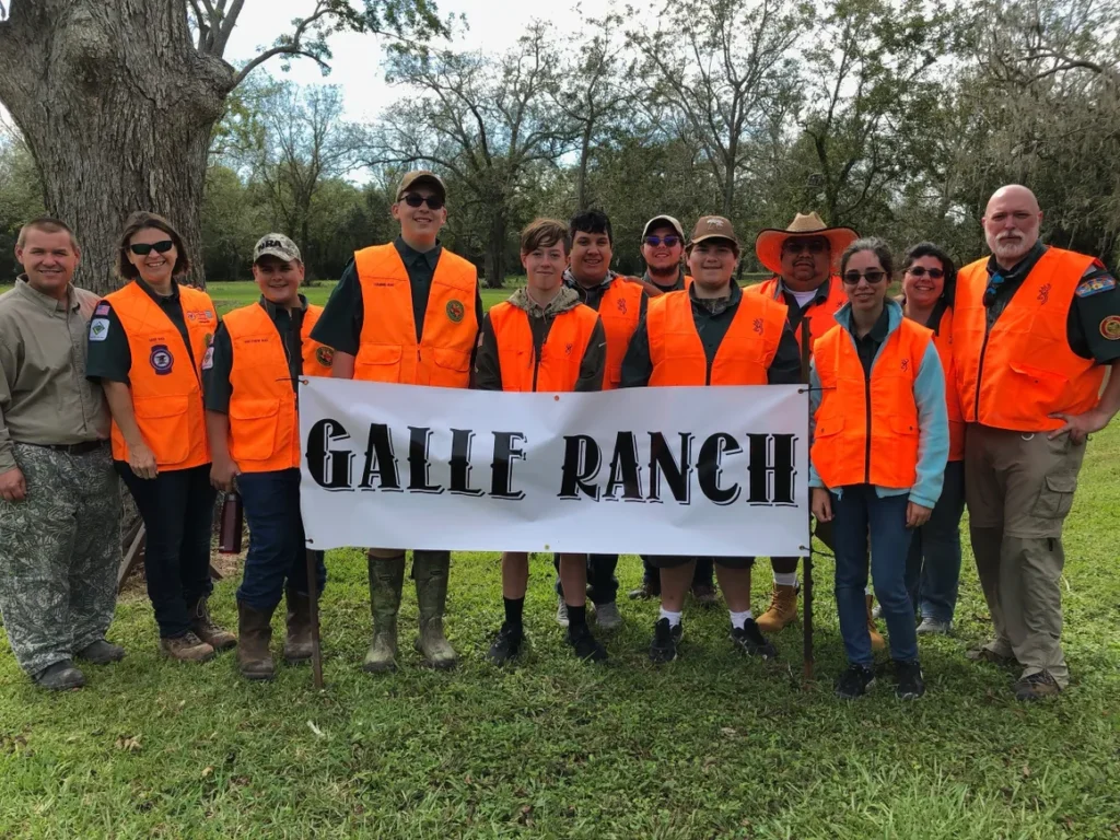 A group of people in orange vests holding an arrow sign.