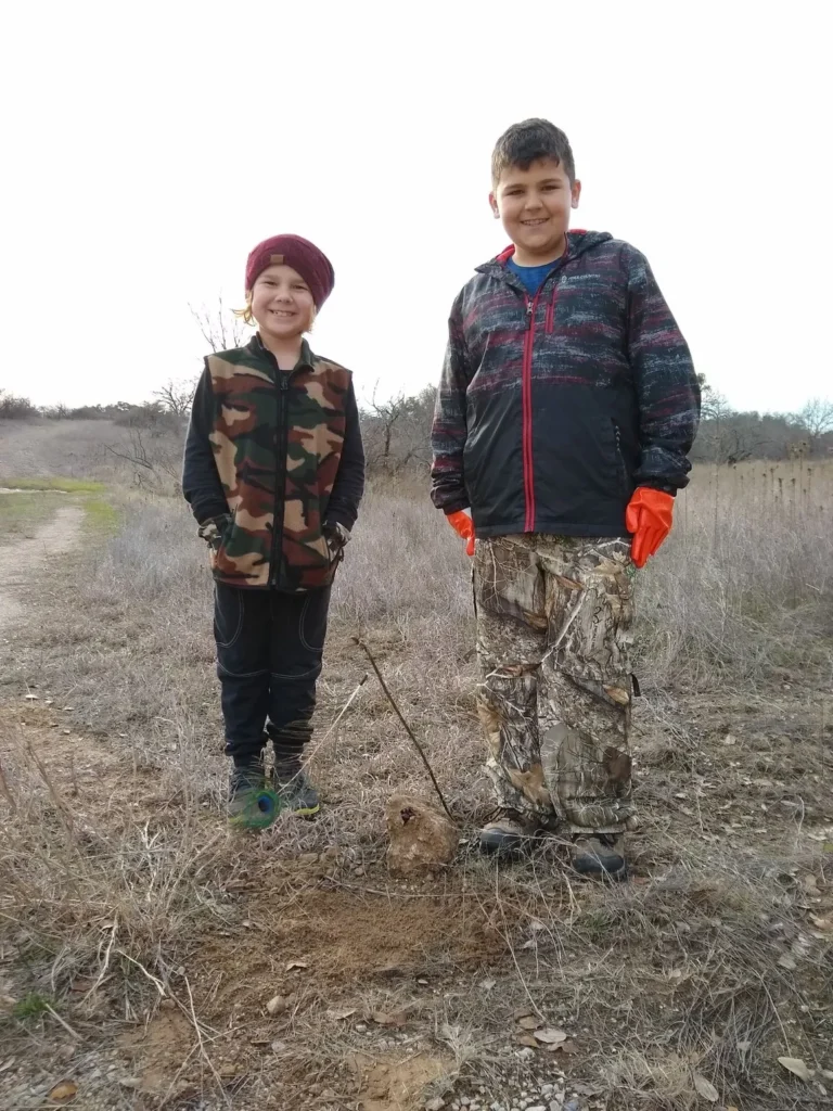 Two boys standing in a field with an arrow.