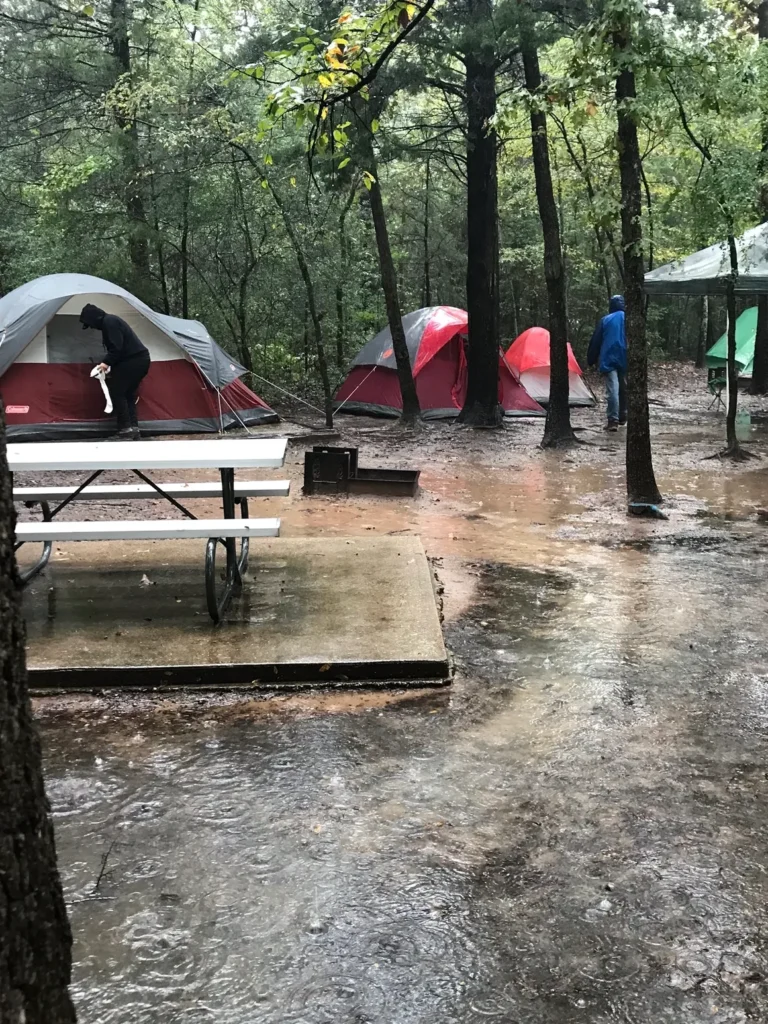 A group of tents in the woods with rain.