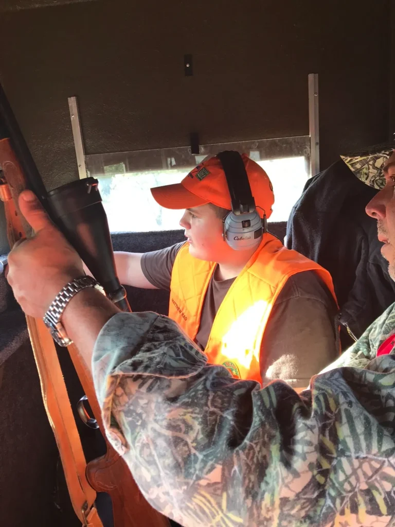 A man in an orange vest holding a gun.