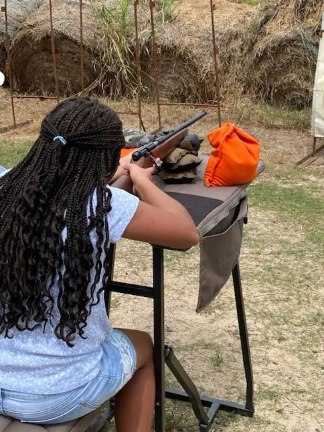 A girl is holding a gun and aiming it.