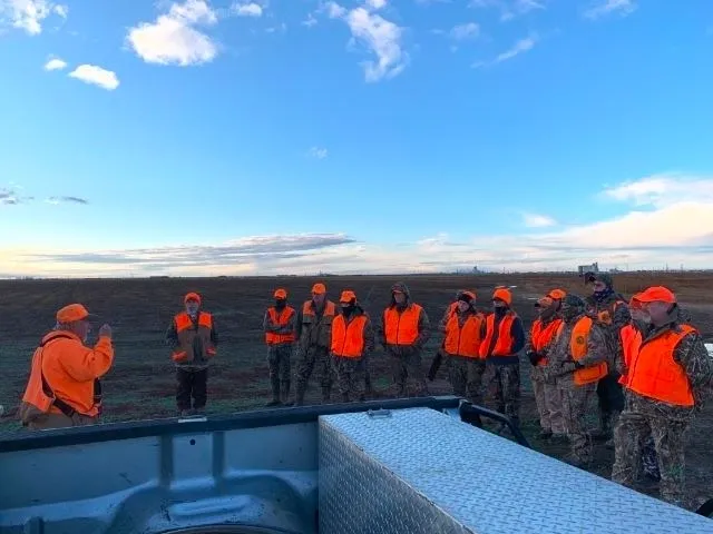 A group of people in orange vests standing around.