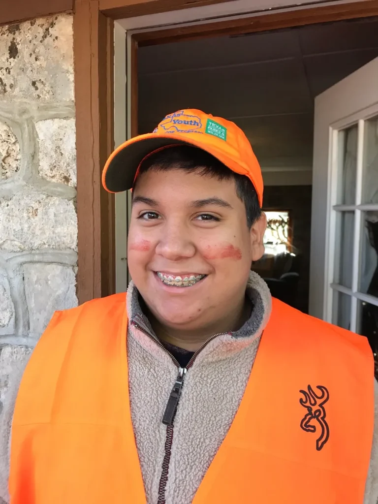 A young man in an orange vest and hat.