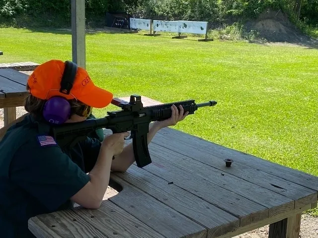 A person sitting on the ground holding an ar-1 5 rifle.