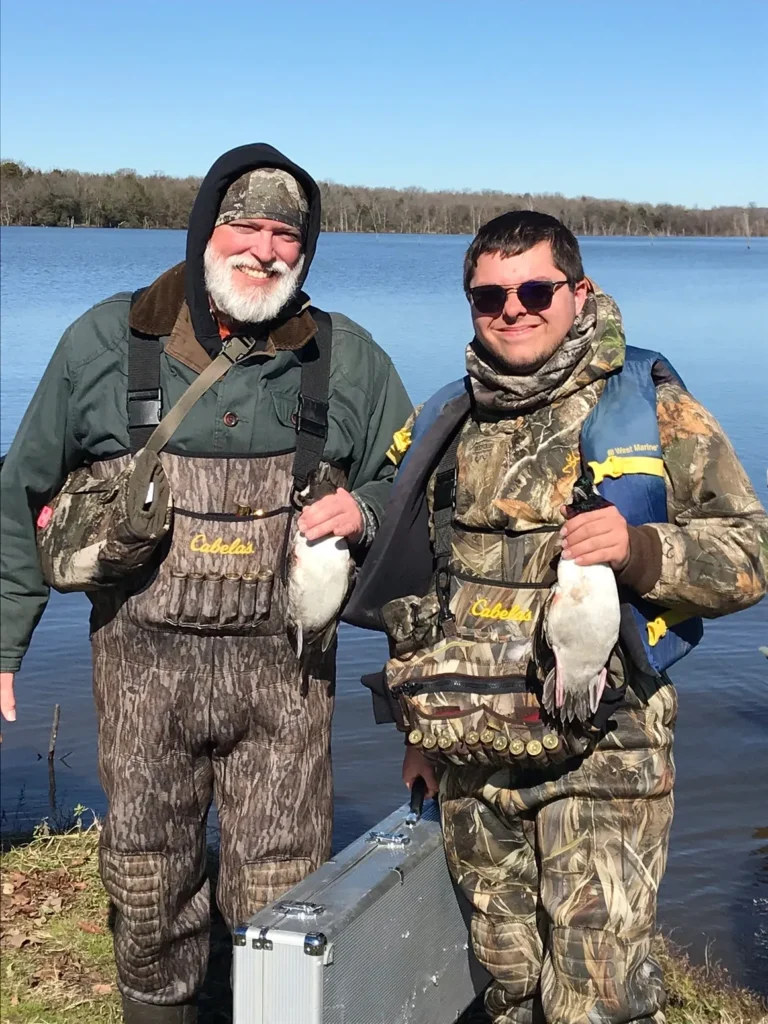 Two men standing next to each other holding fish.