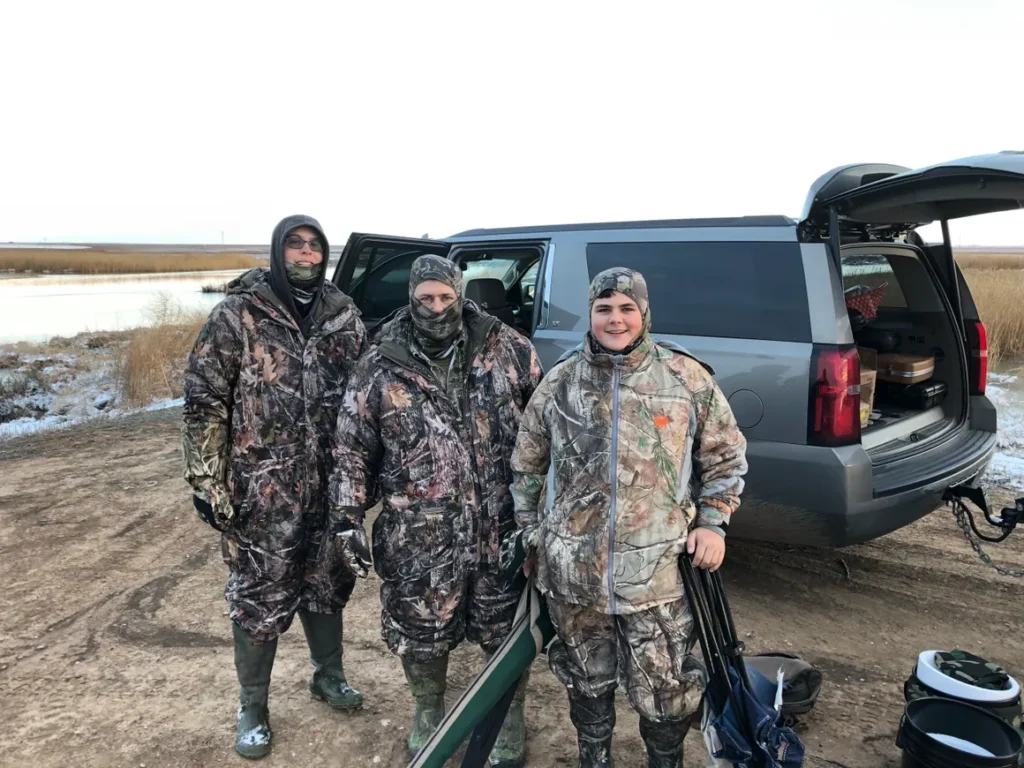 Three hunters standing in front of a truck.