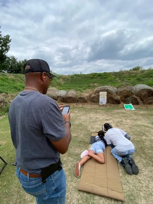 A man taking a picture of two people laying on the ground.