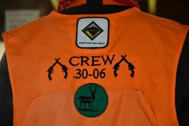 A orange jacket with the words crew 3 0-0 6 and an antelope on it.