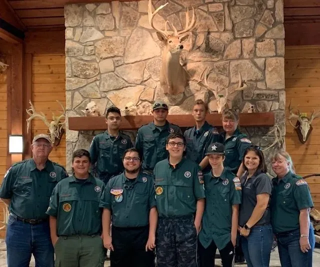 A group of people standing in front of a fireplace.