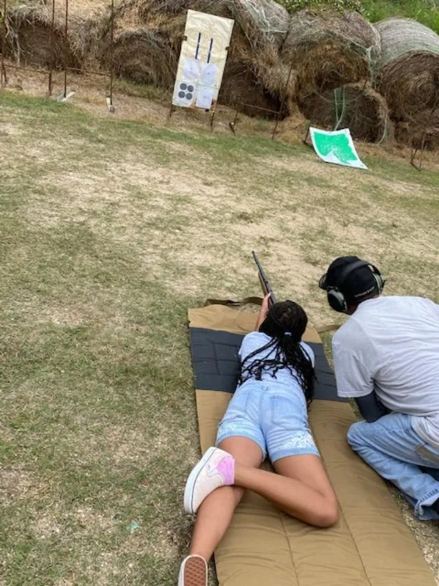 A man and woman shooting guns at an outdoor range.