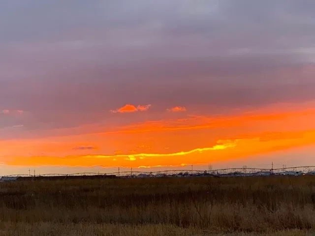 A sunset over the plains with a sky filled with orange clouds.