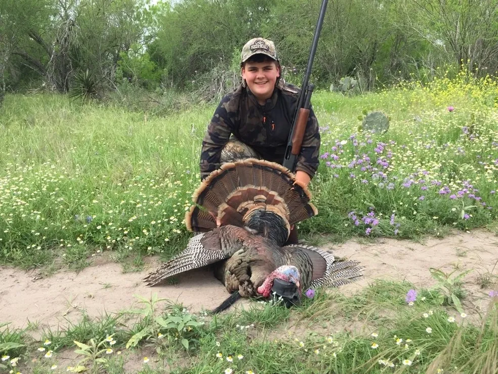 A person sitting on the ground with a turkey