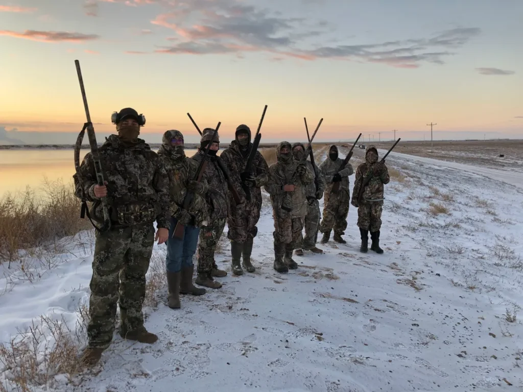A group of people standing in the snow with guns.