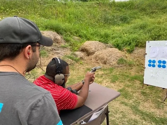 A man holding a gun while another person holds his hand out.