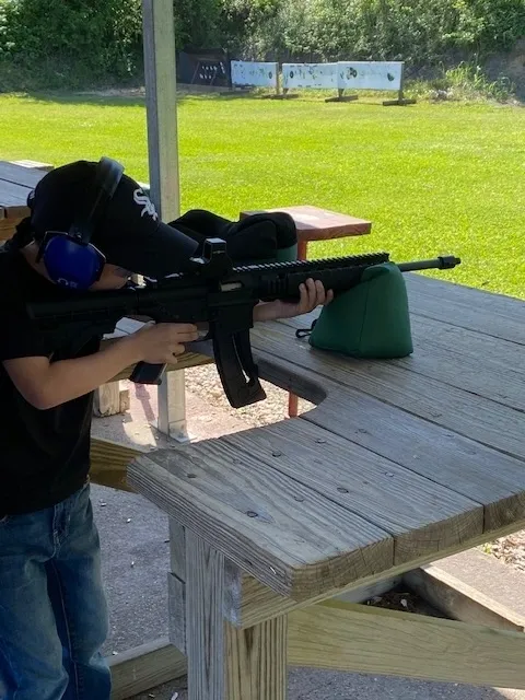 A young boy is holding an ar-1 5 rifle.