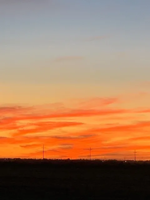 A sunset with clouds in the sky and power lines.