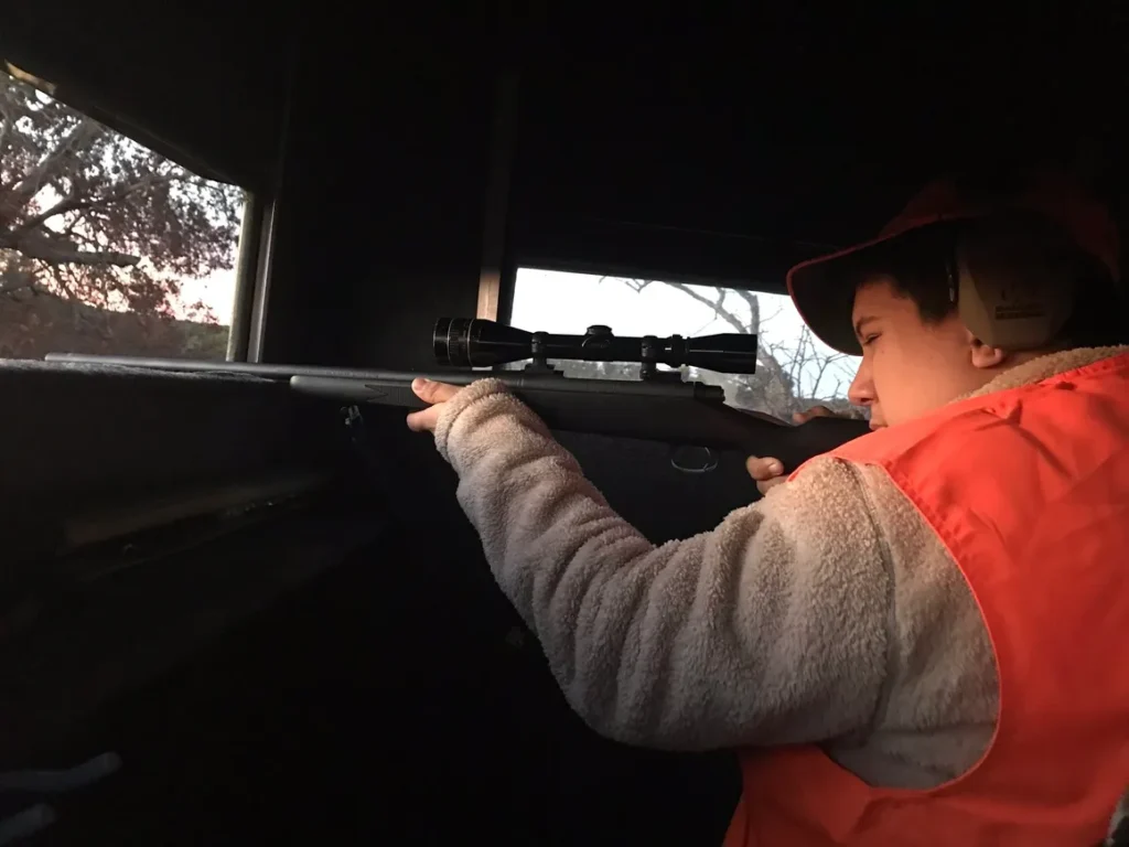 A young boy is holding a rifle in his hand.