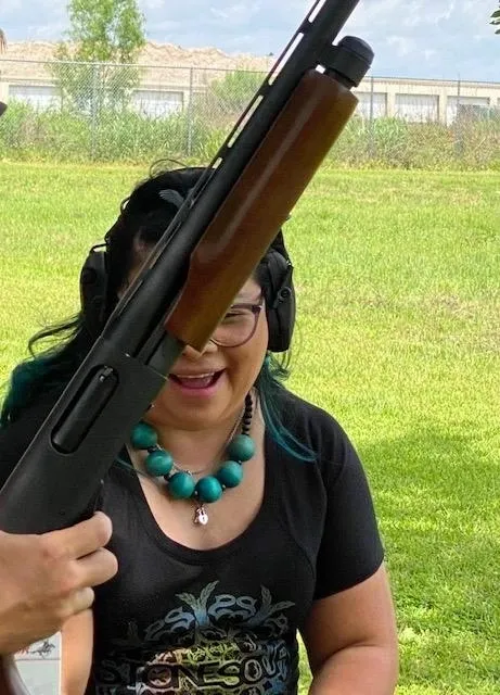 A woman holding onto a gun while wearing a necklace.