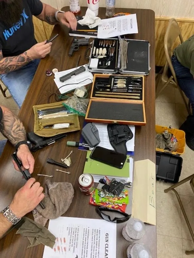 A group of people sitting around a table with various items.