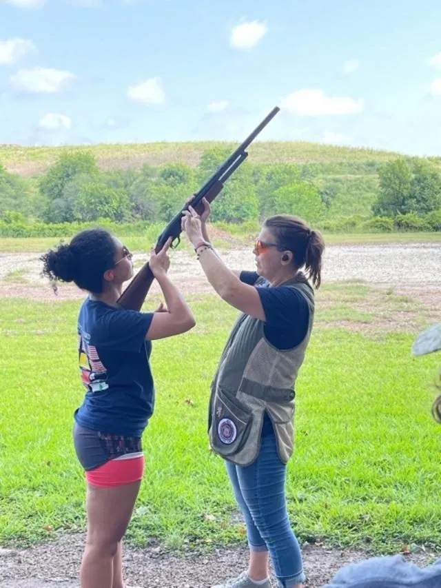 Two women are holding a gun and pointing.