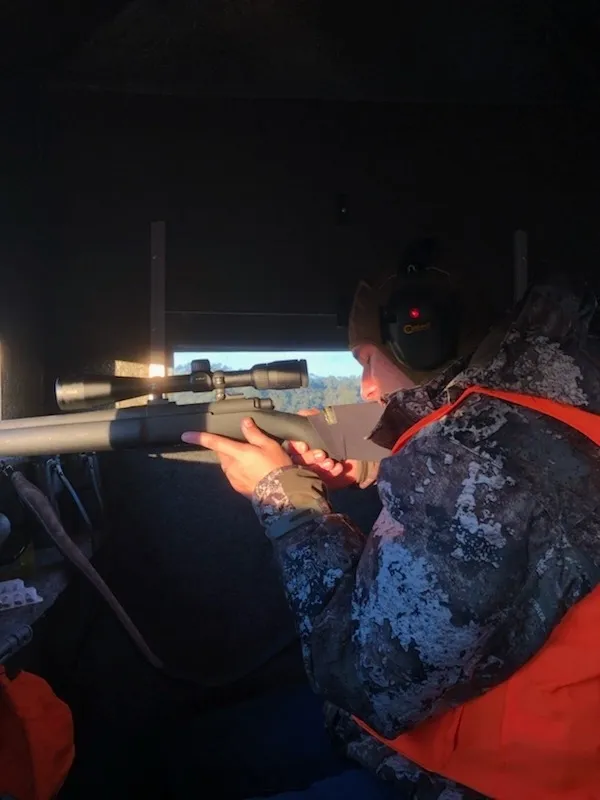 A man in camouflage jacket holding a rifle.