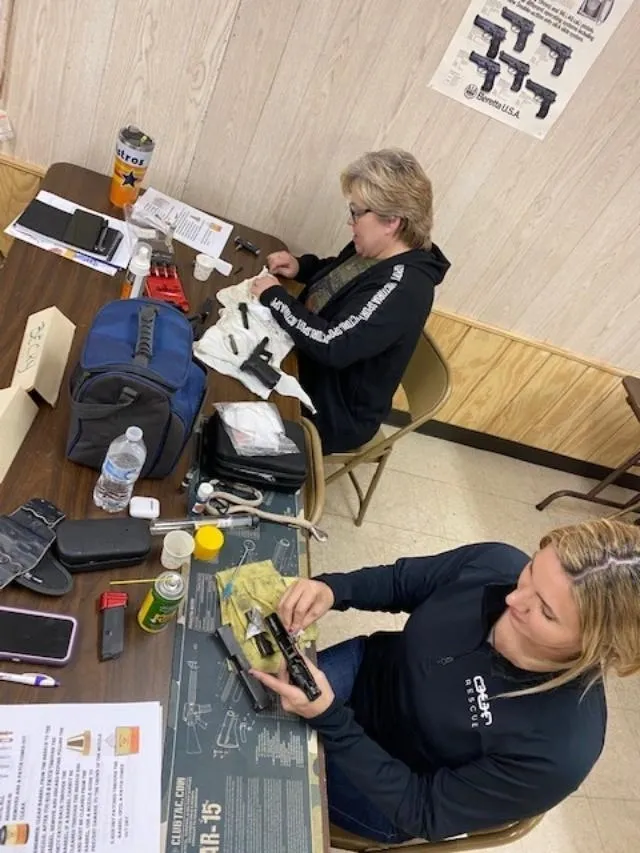 Two women sitting at a table with electronics.