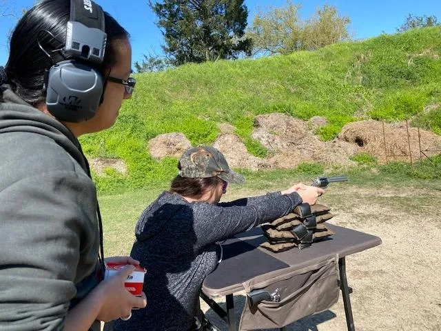 A man is holding a gun while another person holds the trigger.