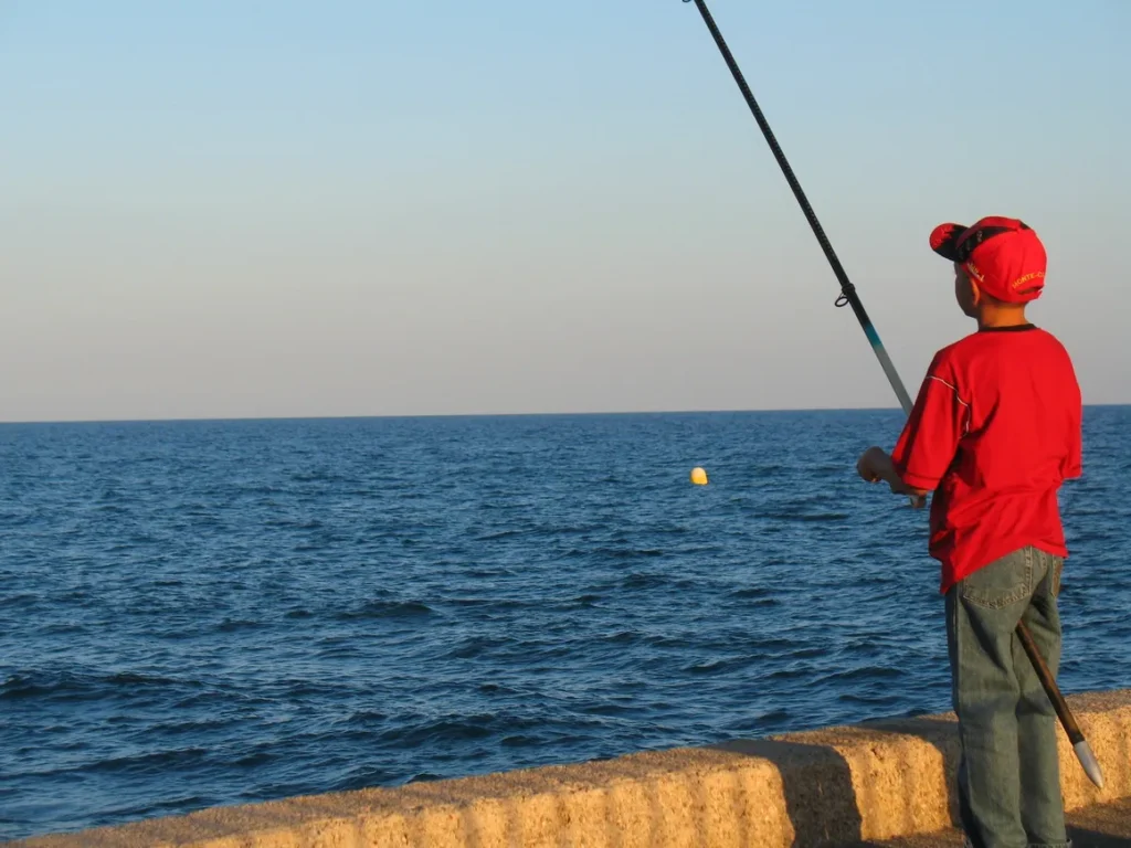 A man fishing on the beach with an ocean in background.