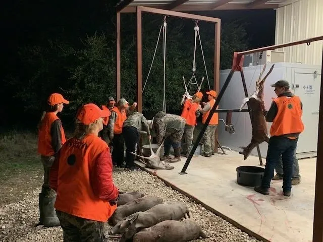 A group of people in orange vests painting a building.