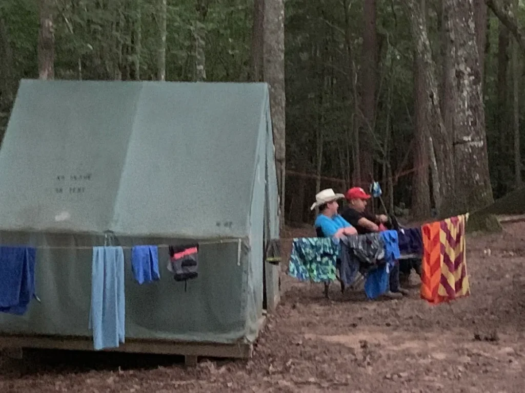 Two people sitting in front of a tent.