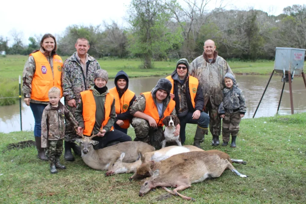 A group of people standing around two deer.