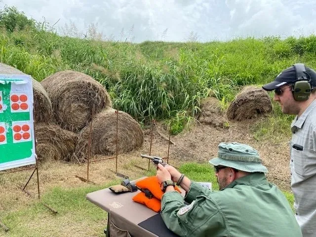 A man in green shirt and hat holding gun.