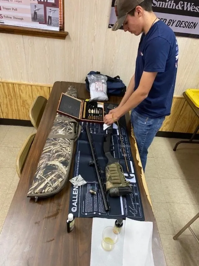 A man standing next to a table with guns.