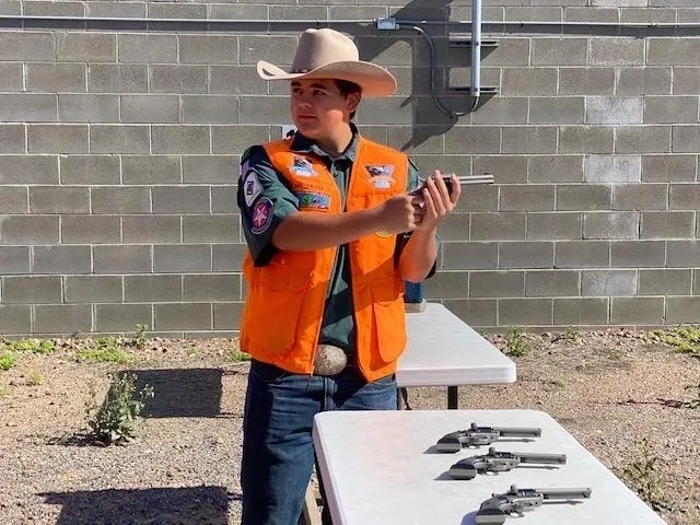 A man in an orange vest holding a gun.