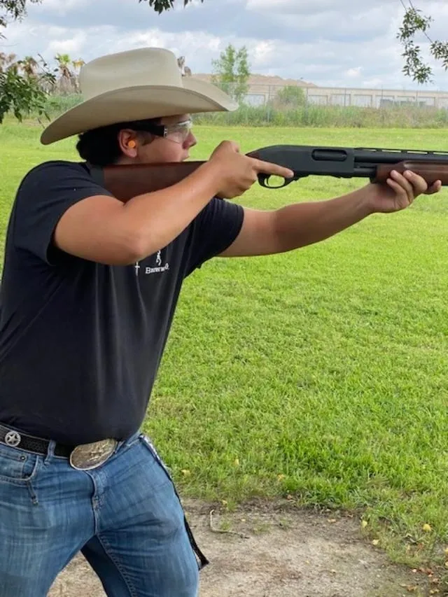A man in cowboy hat holding a gun.