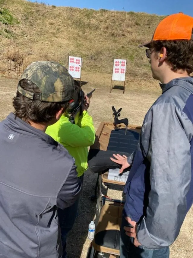 A group of people standing around a shooting range.