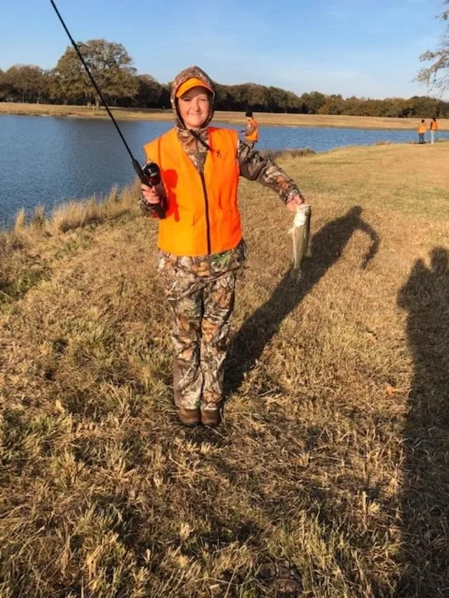 A man in orange vest holding a fish.