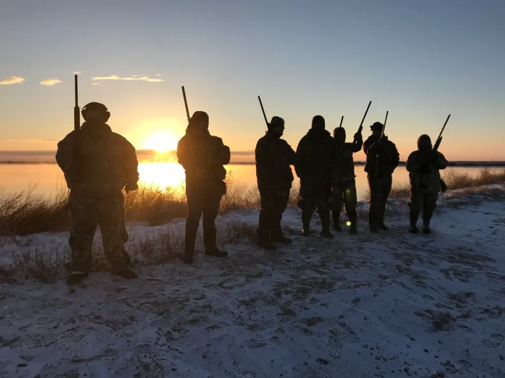 A group of people standing in the snow holding guns.