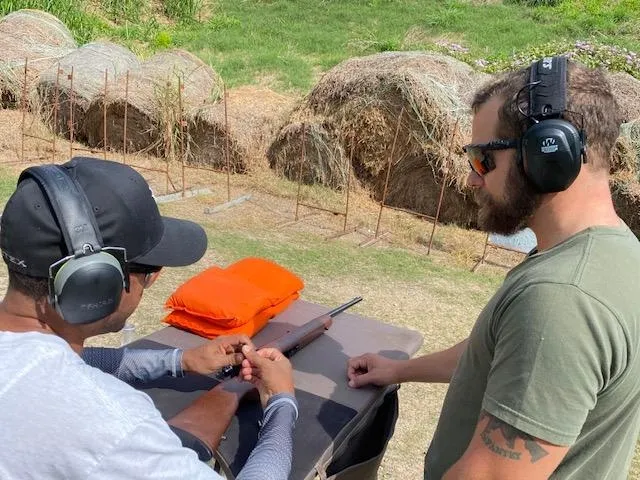 A man in ear muffs and a hat is holding a knife.