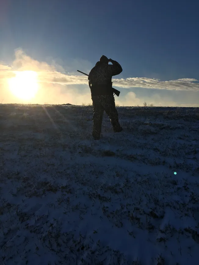 A person standing in the snow with a rifle.