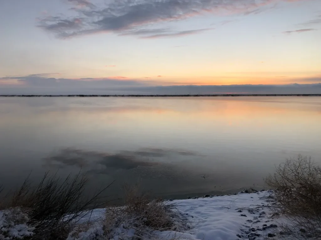 A body of water with snow on the ground