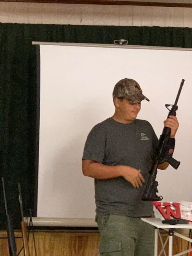A man holding an ar-1 5 rifle in front of a projector screen.