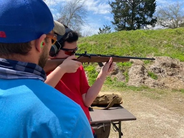 Two men are holding guns and aiming at a target.