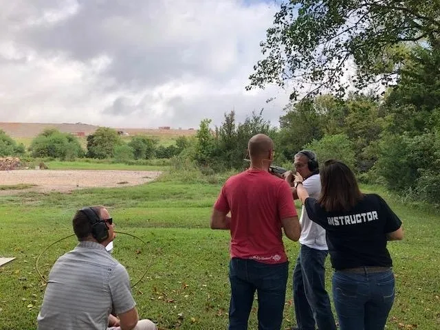 A group of people standing around in the grass.