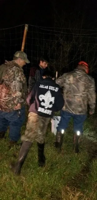 A group of people standing around in the woods.