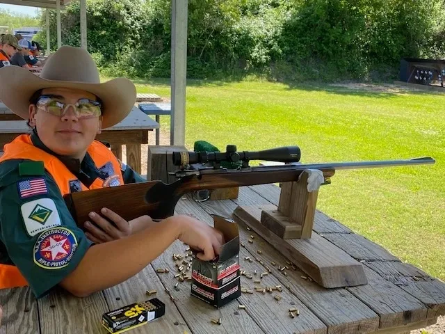 A man sitting on the ground with a rifle.