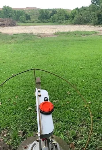 A bow and arrow in the grass with an orange dot on it.