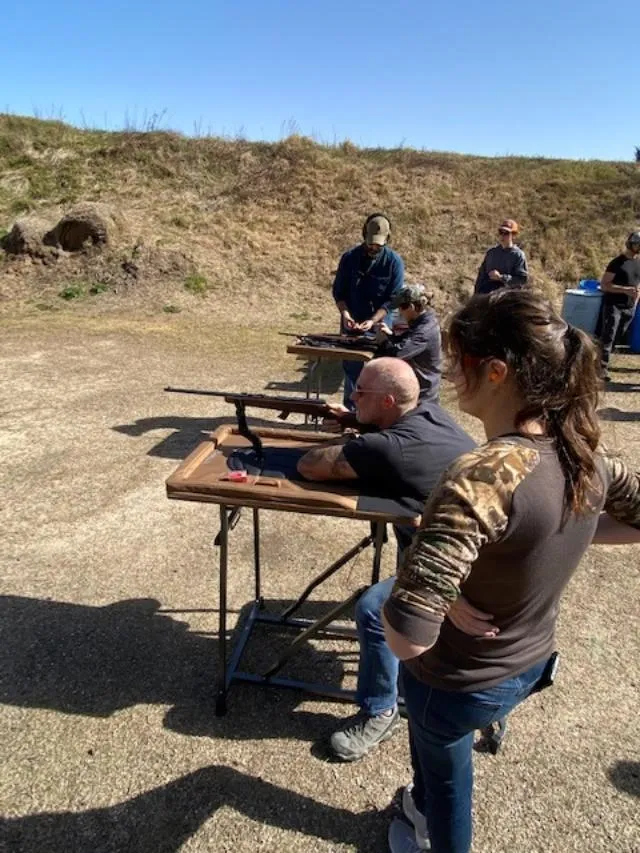 A group of people standing around a table with guns.